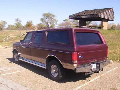 1988 Ford C-350 (Centurion Conversions) - This maroon SUV with tan trim is parked in a lot on a sunny day, showing its rear three-quarter profile.
