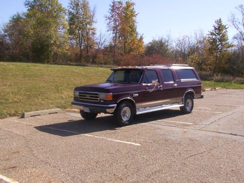 1988 Ford C-350 (Centurion Conversions) - Maroon extended cab pickup truck converted to SUV, parked in a lot with trees in the background.