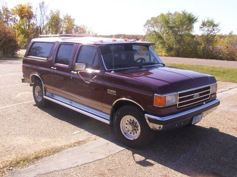 1988 Ford C-350 (Centurion Conversions) - A maroon Ford Centurion conversion van is parked outdoors on a paved surface with trees in the background.