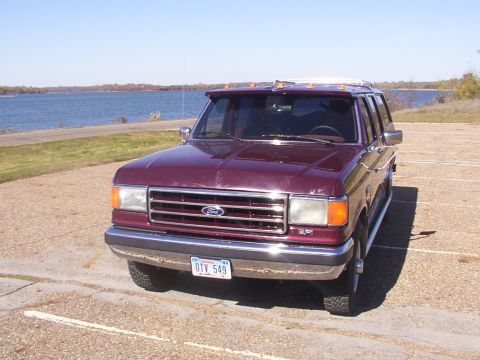 1988 Ford C-350 (Centurion Conversions) - Maroon Ford F-Series truck with Centurion conversion parked by a lake under a clear blue sky.
