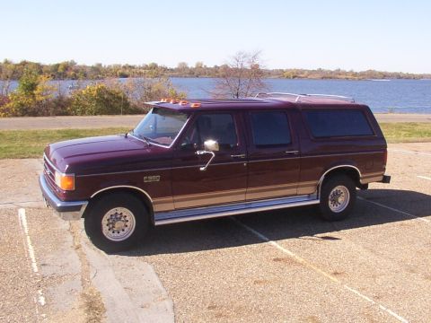 1988 Ford C-350 (Centurion Conversions) - Maroon Ford F-350 Centurion Conversion SUV with tan trim parked near a body of water.
