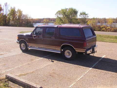 1988 Ford C-350 (Centurion Conversions) - Maroon Ford Bronco Centurion with tan trim, parked in a lot. Rear-view shows tow hitch.