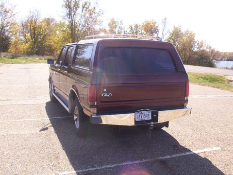 1988 Ford C-350 (Centurion Conversions) - Rear view of a maroon Ford Bronco, likely a 1987 model, parked outdoors with a chrome bumper and roof rack visible.