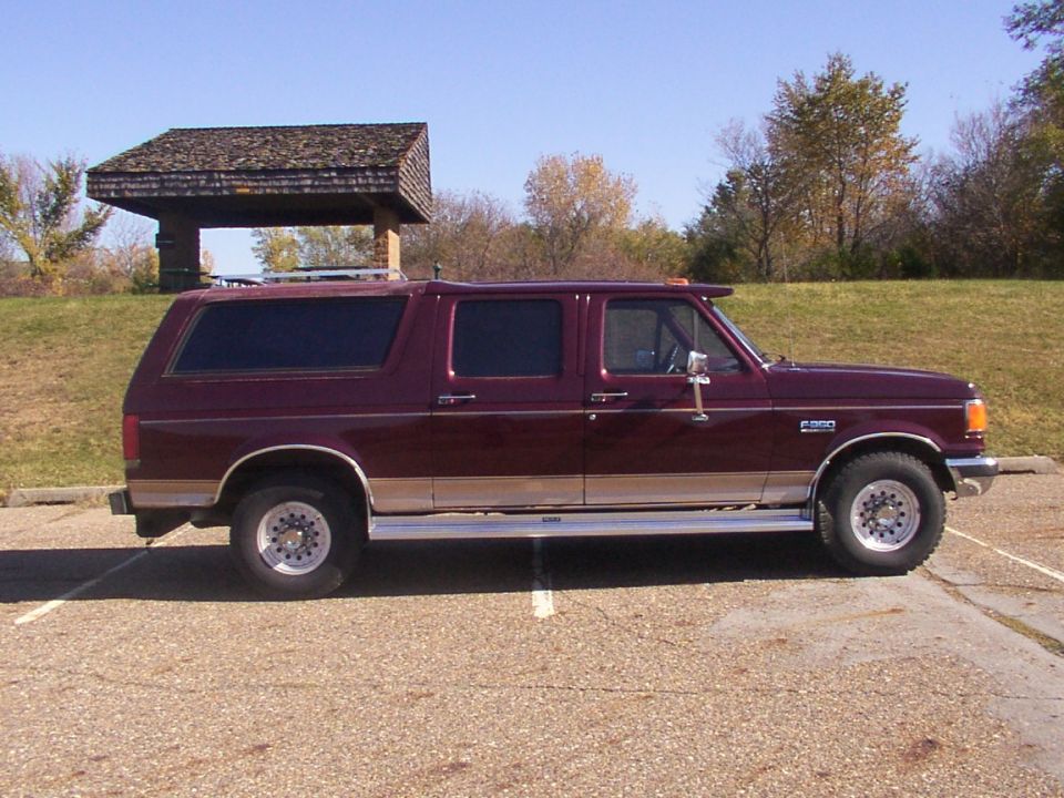 Maroon SUV with tan trim, side view. Looks like a Ford F-250/F-350 based conversion
