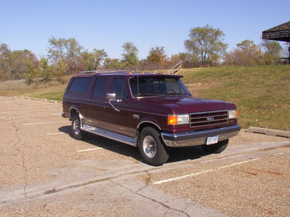 Maroon SUV with chrome trim and a sun visor parked in a lot