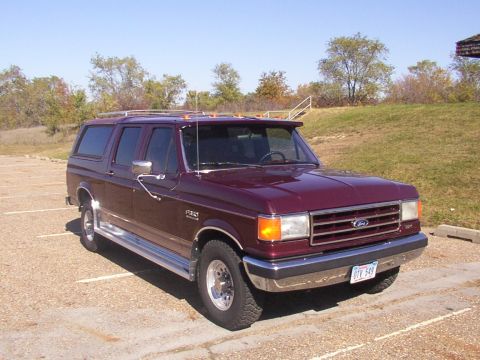 1988 Ford C-350 (Centurion Conversions) - Maroon Ford F-Series SUV conversion parked in a lot under a clear sky.