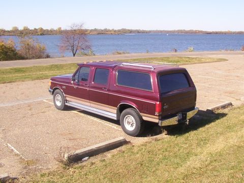 1988 Ford C-350 (Centurion Conversions) - This maroon extended cab pickup truck, likely a 1987 model, is parked near a body of water on a sunny day.