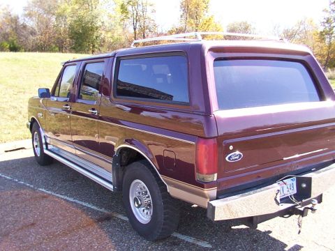 1988 Ford C-350 (Centurion Conversions) - This maroon SUV features a chrome trim package and a roof rack, seen from the rear three-quarter angle.