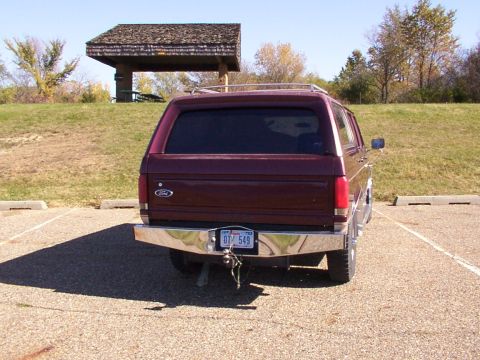 1988 Ford C-350 (Centurion Conversions) - Maroon Ford Bronco parked in a lot with a picnic shelter in the background.