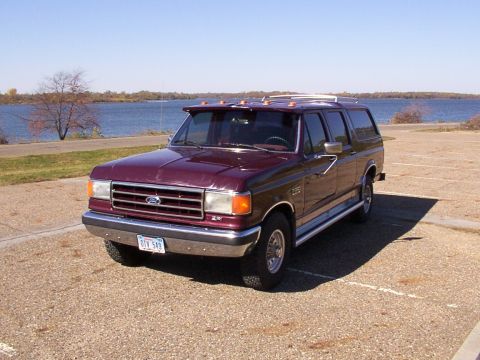 1988 Ford C-350 (Centurion Conversions) - Maroon Ford C-350 Centurion Conversion SUV parked by a lake on a sunny day.