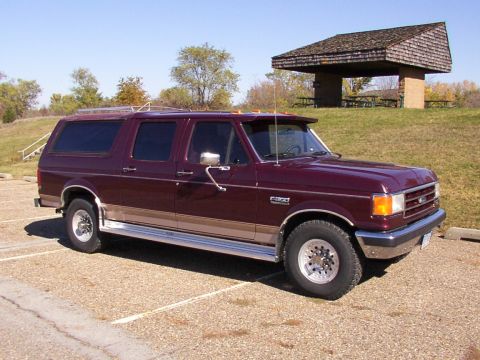 1988 Ford C-350 (Centurion Conversions) - A maroon Ford SUV conversion with tan trim is parked in a lot near a picnic shelter.