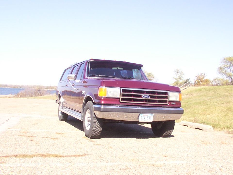 Maroon Ford Bronco Centurion with a sun visor parked near a body of water