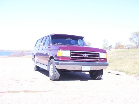 1988 Ford C-350 (Centurion Conversions) - Maroon Ford C-350 Centurion Conversion Van with a sun visor, parked outdoors near a body of water.