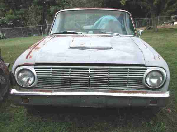Front of a weathered 1960-1963 Ford Falcon Ranchero with a horizontal bar grille and a hood scoop
