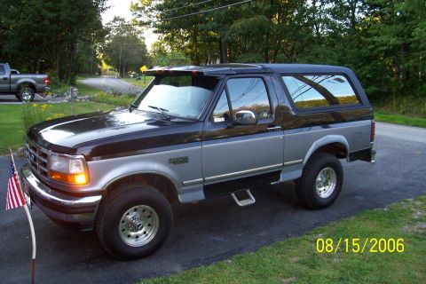 1995 Ford Bronco - A two-tone black and silver 1995 Ford Bronco is parked in a driveway with an American flag.