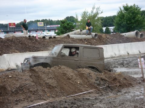 1988 Suzuki Samurai - A Suzuki Samurai struggles through a muddy obstacle course, with spectators watching from the sidelines.