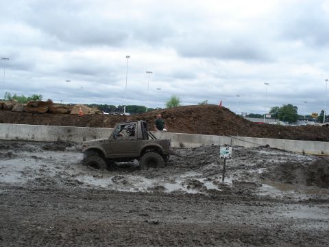 1988 Suzuki Samurai - A 1988 Suzuki Samurai navigates a challenging mud bog course under a cloudy sky.