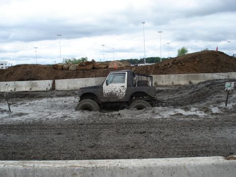 1988 Suzuki Samurai - A vehicle navigates a challenging mud bog course under a cloudy sky.