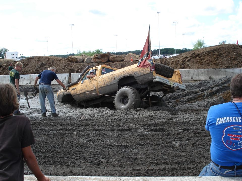 Yellow pickup truck stuck in mud, with a Confederate flag on the back