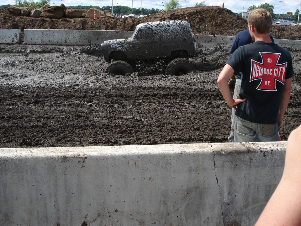 Off-road vehicle partially submerged in thick mud, with spectators watching