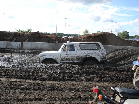 1988 Suzuki Samurai - A white SUV is stuck deep in mud during an off-road event.
