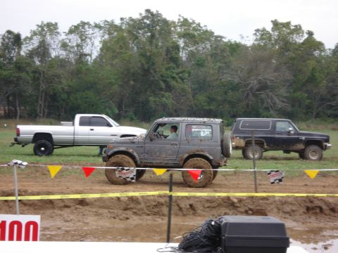 1988 Suzuki Samurai - A Suzuki Samurai navigates a mud bog course, with other off-road vehicles visible in the background.