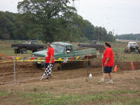 1988 Suzuki Samurai - Multiple trucks participate in a mud bogging event, with one green truck struggling in the mire.