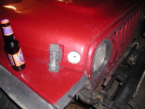 1998 Jeep TJ - A red Jeep hood is shown with a bottle of beer and a hood latch. The registry claims it is a 1998 Jeep TJ, but the visible details do not c…