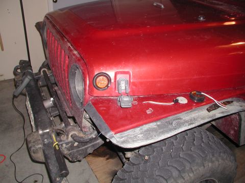 1998 Jeep TJ - The front quarter panel of a red Jeep Wrangler shows exposed wiring and a partially removed fender flare.