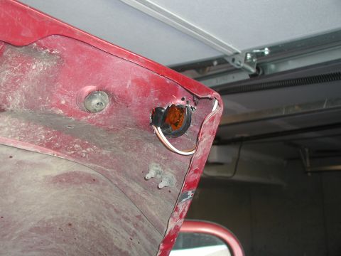 1998 Jeep TJ - Interior of a red car hood shows damage around the turn signal housing.