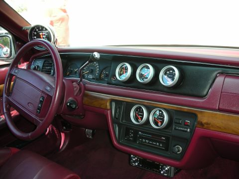 1992 Ford Crown Victoria - Interior dashboard view of a car with burgundy/maroon leather trim and wood-grain accents, showing the steering wheel, factory instrument c…