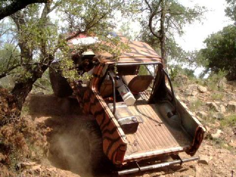 1984 Ford Bronco - This heavily modified off-road truck, likely from the early 1980s, navigates a rocky incline.