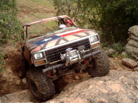 1984 Ford Bronco - This off-road vehicle navigates challenging rocky terrain, sporting a distinctive Texas flag paint scheme.