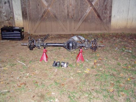 1989 Ford F-250 - A disassembled front axle assembly rests on jack stands in front of a wooden barn door.