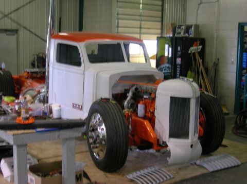 1989 Ford Bronco - A custom truck cab is shown in a workshop with its engine exposed and chrome wheels.