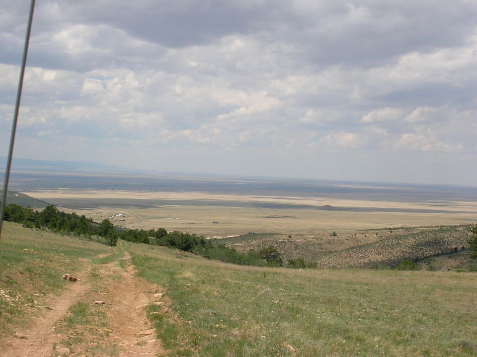 Off-road trail leading to a wide, arid landscape under a cloudy sky