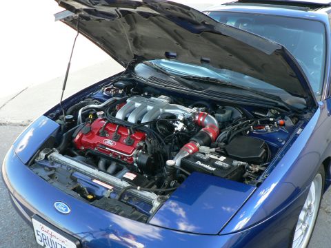 1995 Ford Probe - The engine bay of a blue 1995 Ford Probe is visible with the hood open, revealing the V6 engine.