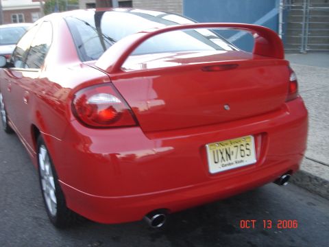 2005 Dodge SRT-4 - Rear view of a red Dodge Neon SRT-4 with a prominent spoiler and dual exhaust pipes, parked on a street.