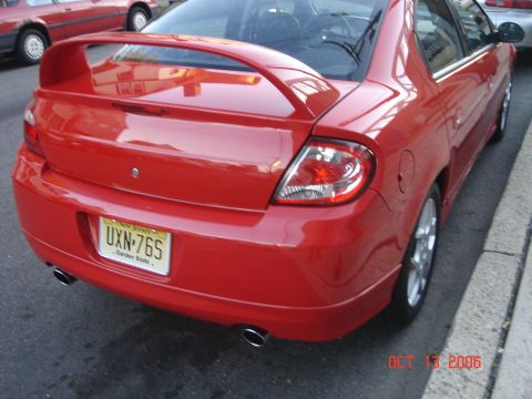 2005 Dodge SRT-4 - A red Dodge Neon sedan is parked on the street, showing its rear spoiler and dual exhaust pipes.
