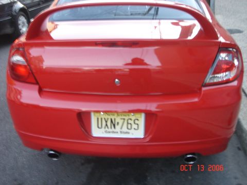 2005 Dodge SRT-4 - Rear view of a red Dodge Neon SRT-4 with a spoiler and dual exhaust pipes, parked outdoors.