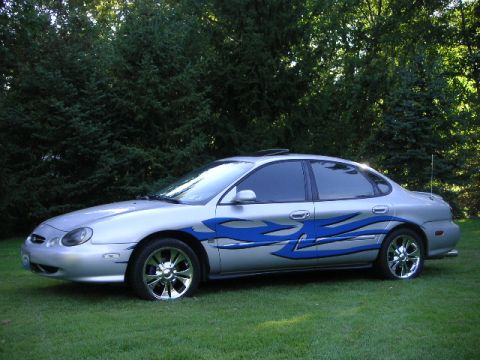1999 Ford Taurus - Silver 1999 Ford Taurus with custom blue flame graphics and chrome wheels.