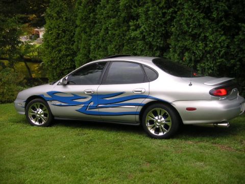 1999 Ford Taurus - This sedan features custom blue flame decals along its side, with chrome wheels and a spoiler.