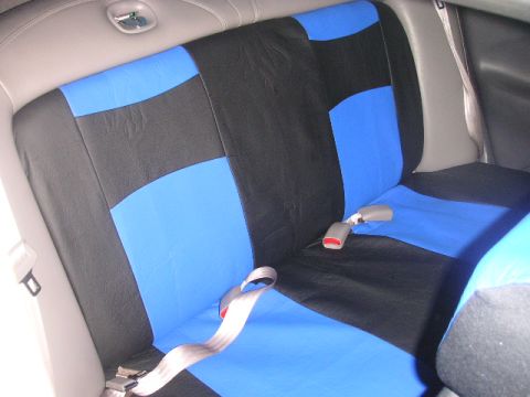 1999 Ford Taurus - The rear seat of a car features custom blue and black seat covers with visible seatbelts.