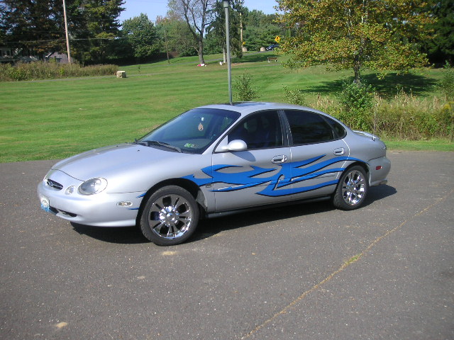 Silver sedan with blue flame decals on the side, parked on asphalt