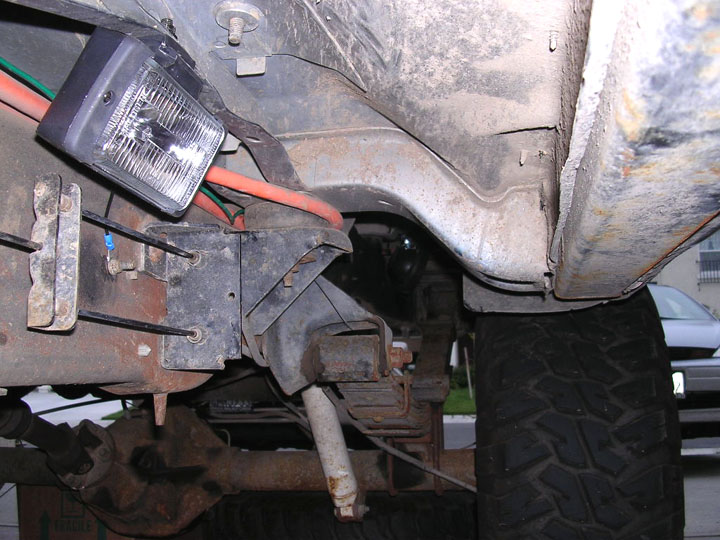 Undercarriage showing a rectangular headlight, frame and inner fender of a truck