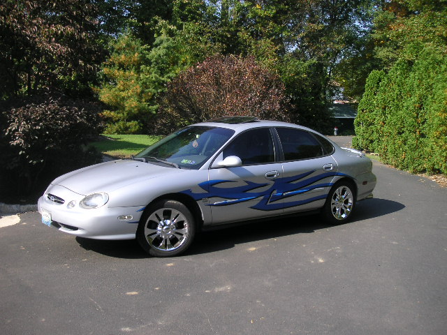 Silver 1999 Ford Taurus with blue flame decals