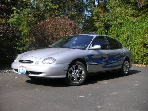 1999 Ford Taurus - Silver 1999 Ford Taurus sedan with custom blue flame graphics on the side.