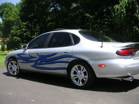 1999 Ford Taurus - This 1999 Ford Taurus features custom blue tribal graphics and chrome wheels, seen from the rear 3/4 angle.