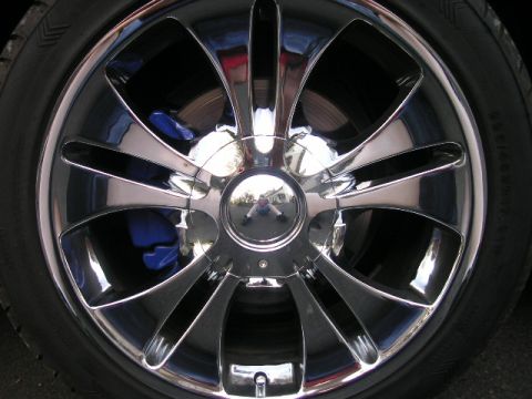 1999 Ford Taurus - Close-up of a shiny chrome wheel and blue brake caliper.