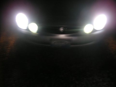 1999 Ford Taurus - Front view of a car at night with headlights on, obscuring details of the vehicle.